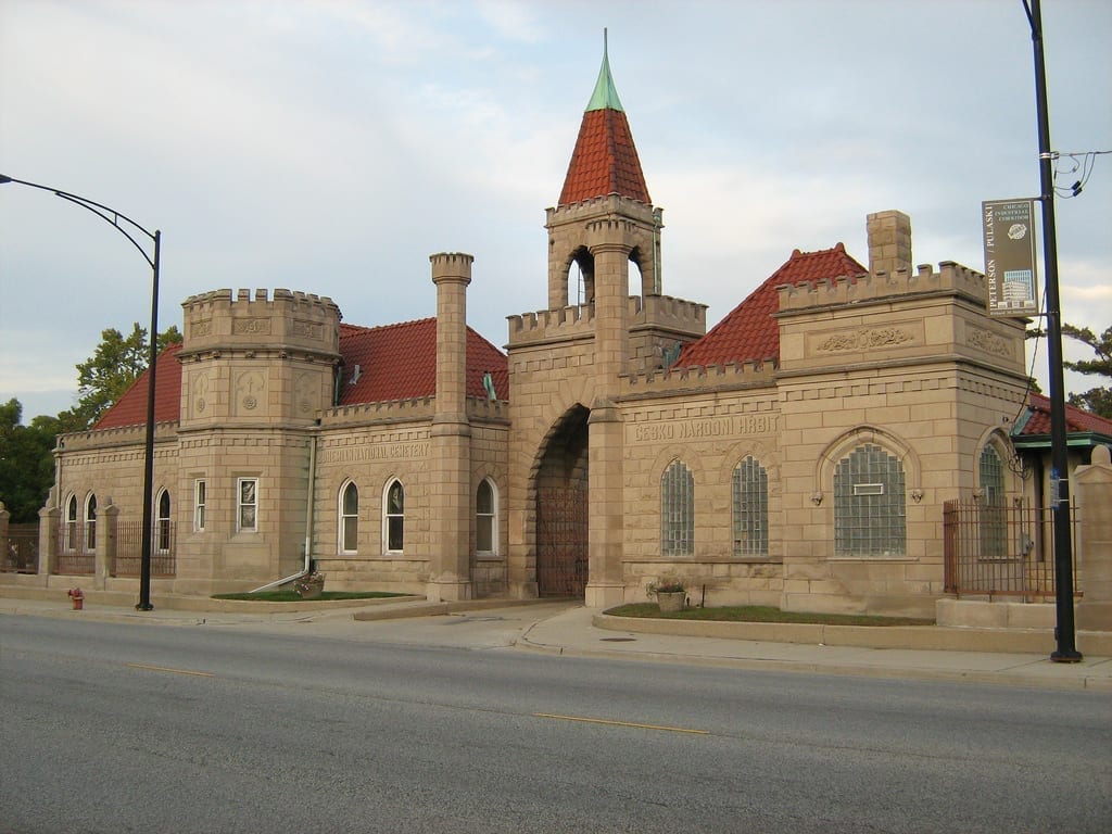 The castle-like stone entrance gate of Bohemian National Cemetery in Chicago, with a red-tiled turret and arched carriage entrance.