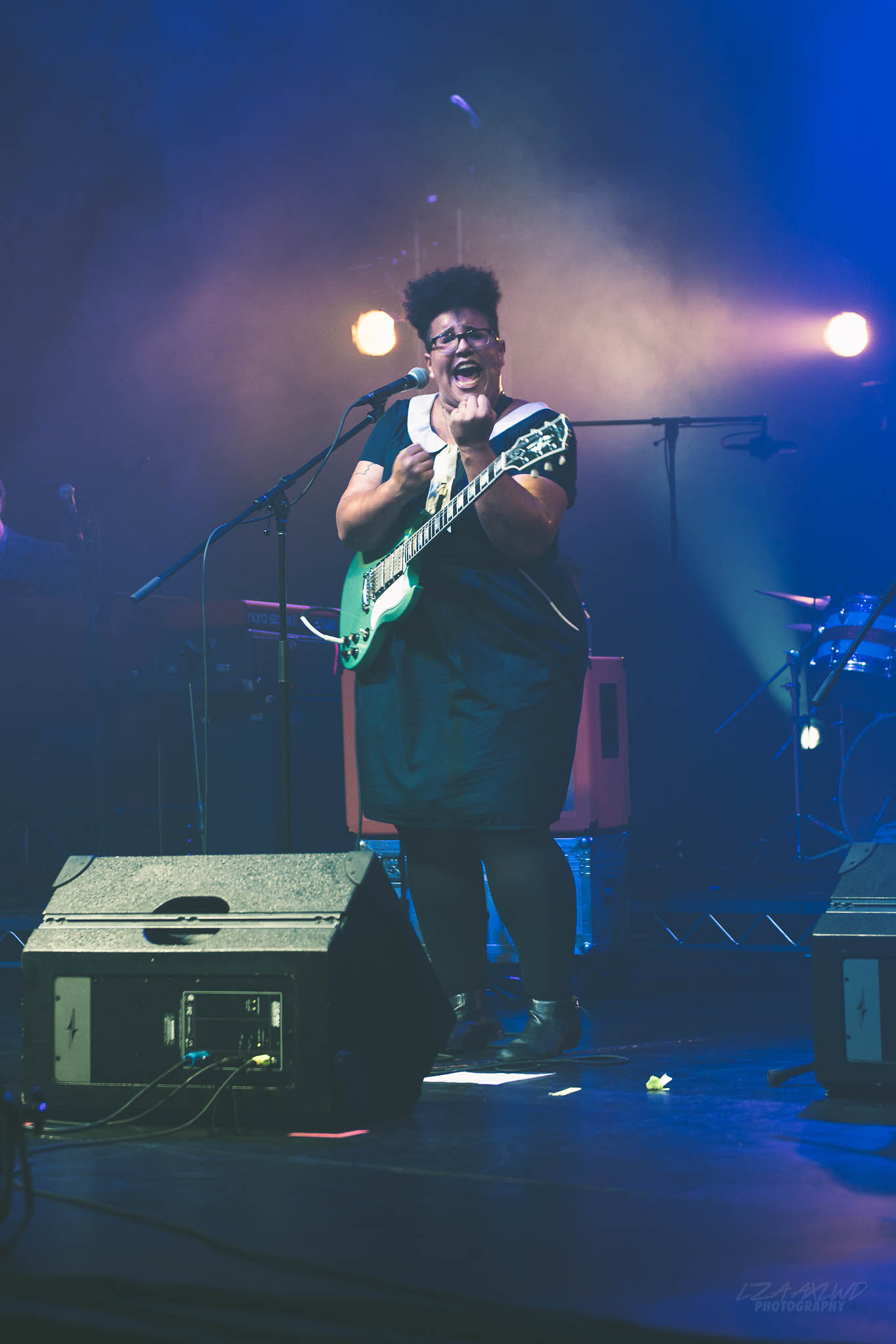 Brittany Howard leans back mid-note with a hollow-body electric guitar, eyes closed, under warm stage light.