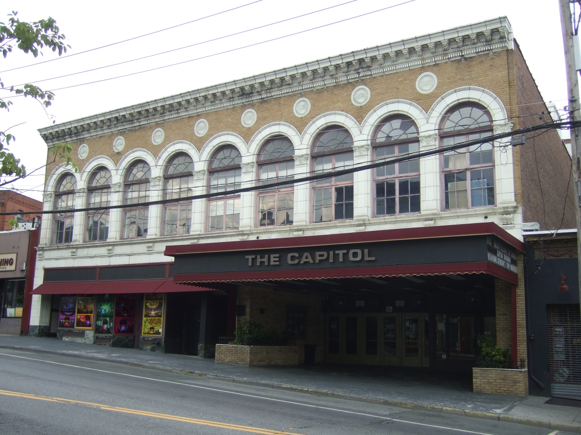Street view of The Capitol Theatre in Port Chester, a two-storey brick building with tall arched windows and a dark marquee reading THE CAPITOL over the entrance