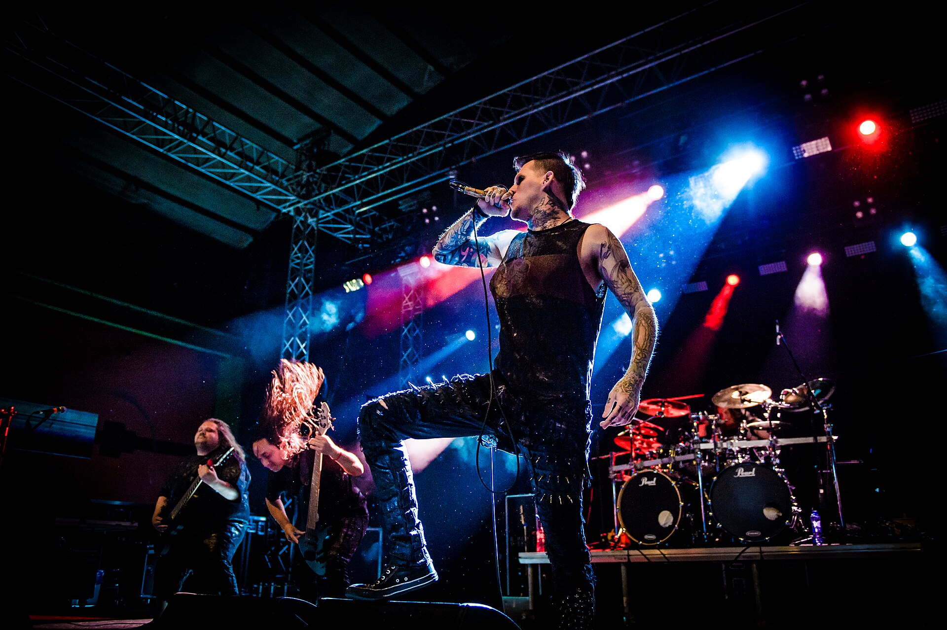 Carnifex play a hall lit red and blue: the tattooed singer plants one boot on a monitor and screams into a handheld mic while two guitarists headbang behind him.