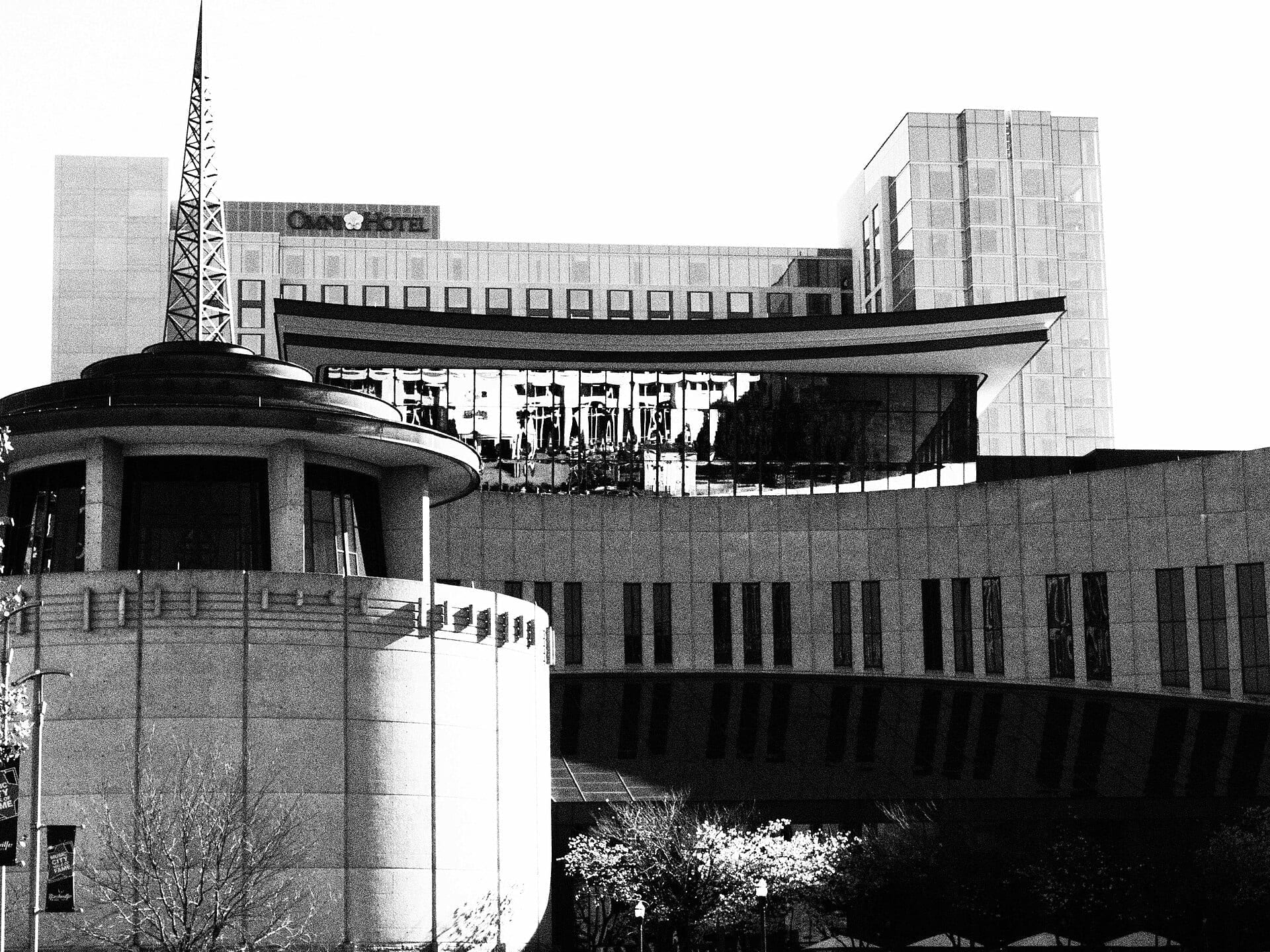 A black and white photo of the Country Music Hall of Fame and Museum in Nashville, its curved facade designed to evoke a piano, with the radio-tower spire visible behind it.