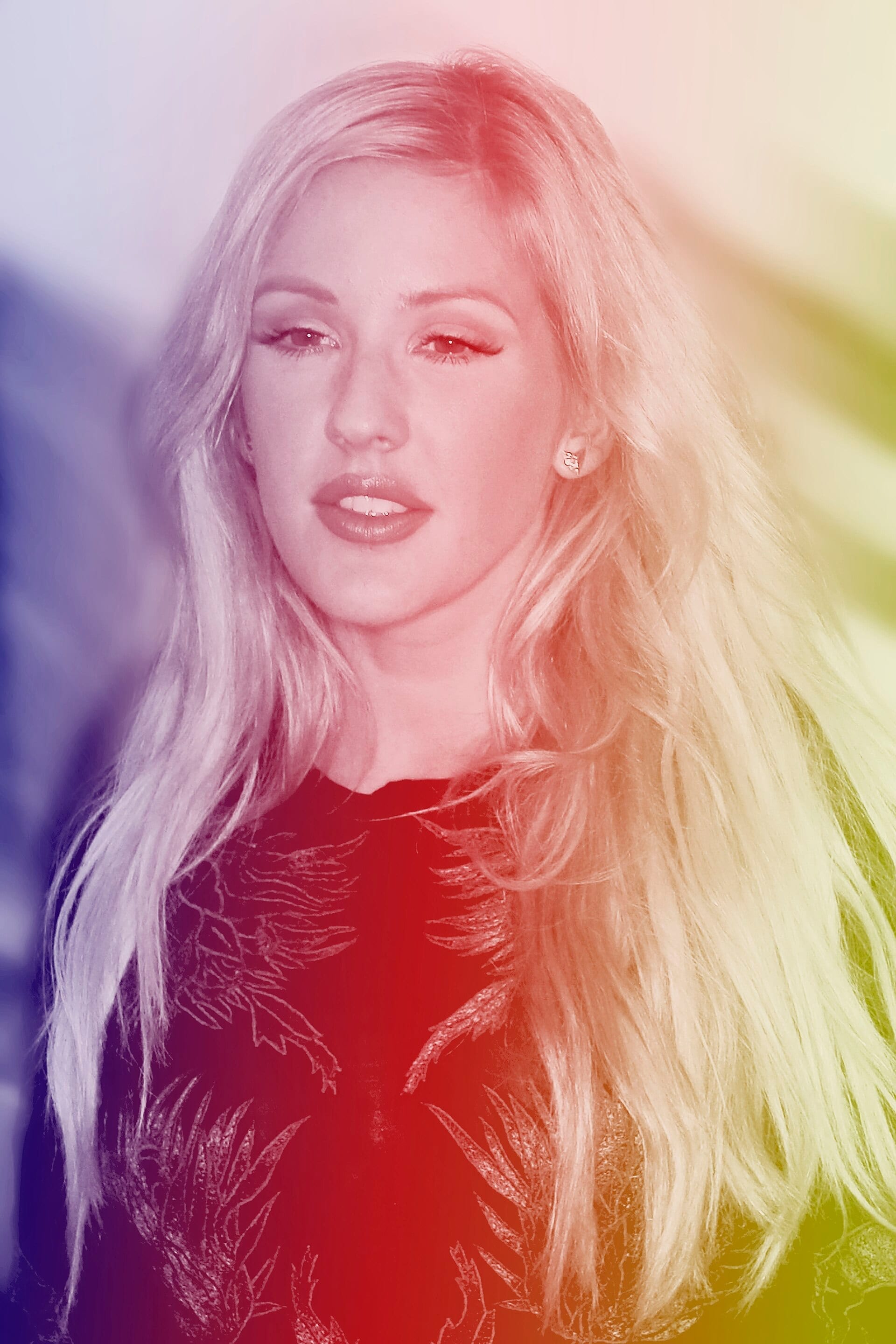 A close-up portrait of Ellie Goulding with long blond hair, shown through a rainbow-tinted color filter.