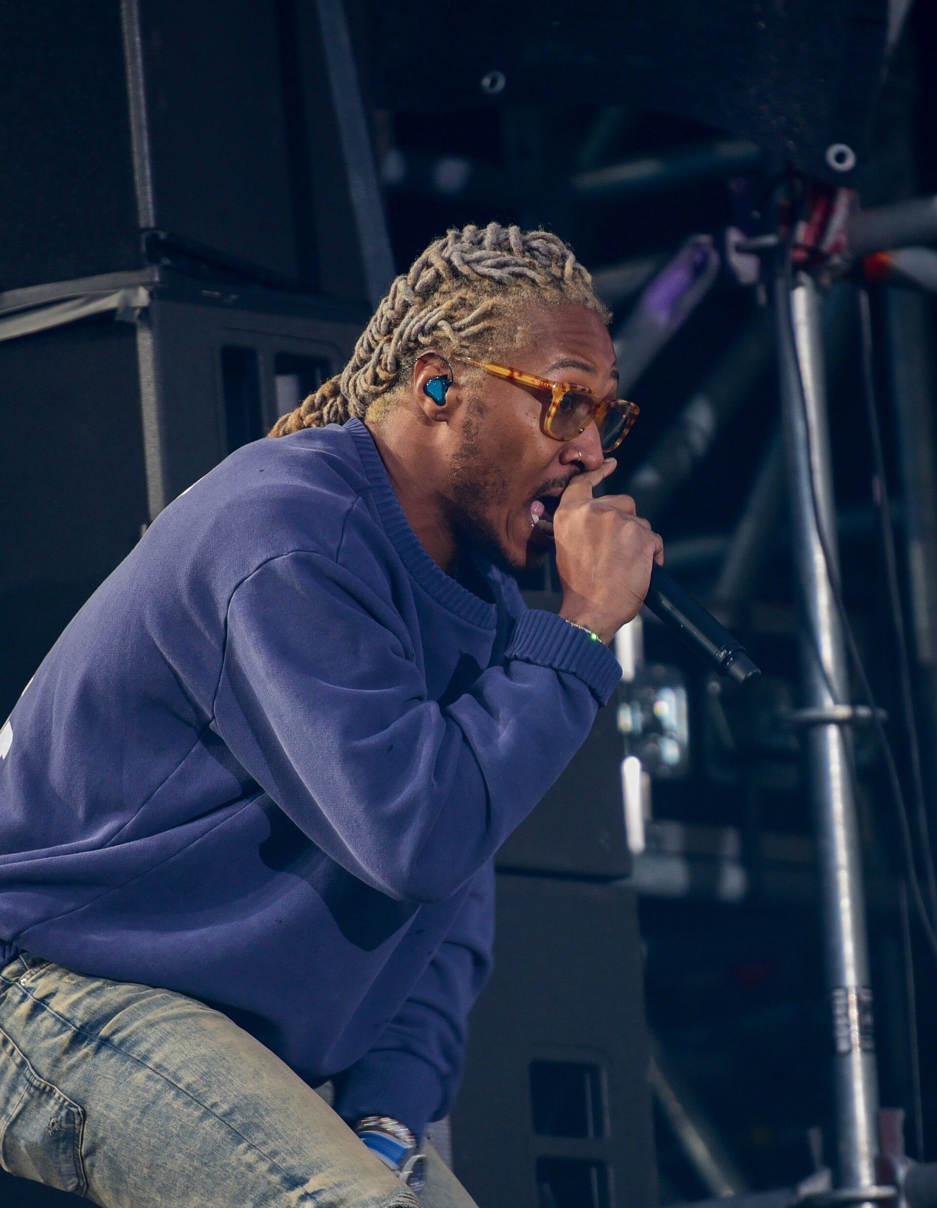 Future performs in side profile, dreadlocks pulled back, wearing tortoiseshell glasses and a purple sweatshirt, holding a microphone to his mouth mid-verse.