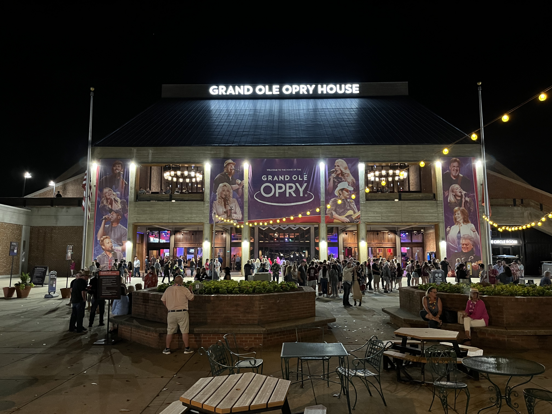 The Grand Ole Opry House lit at night, its long brick front and glass entrance under a lit sign, with the forecourt empty.