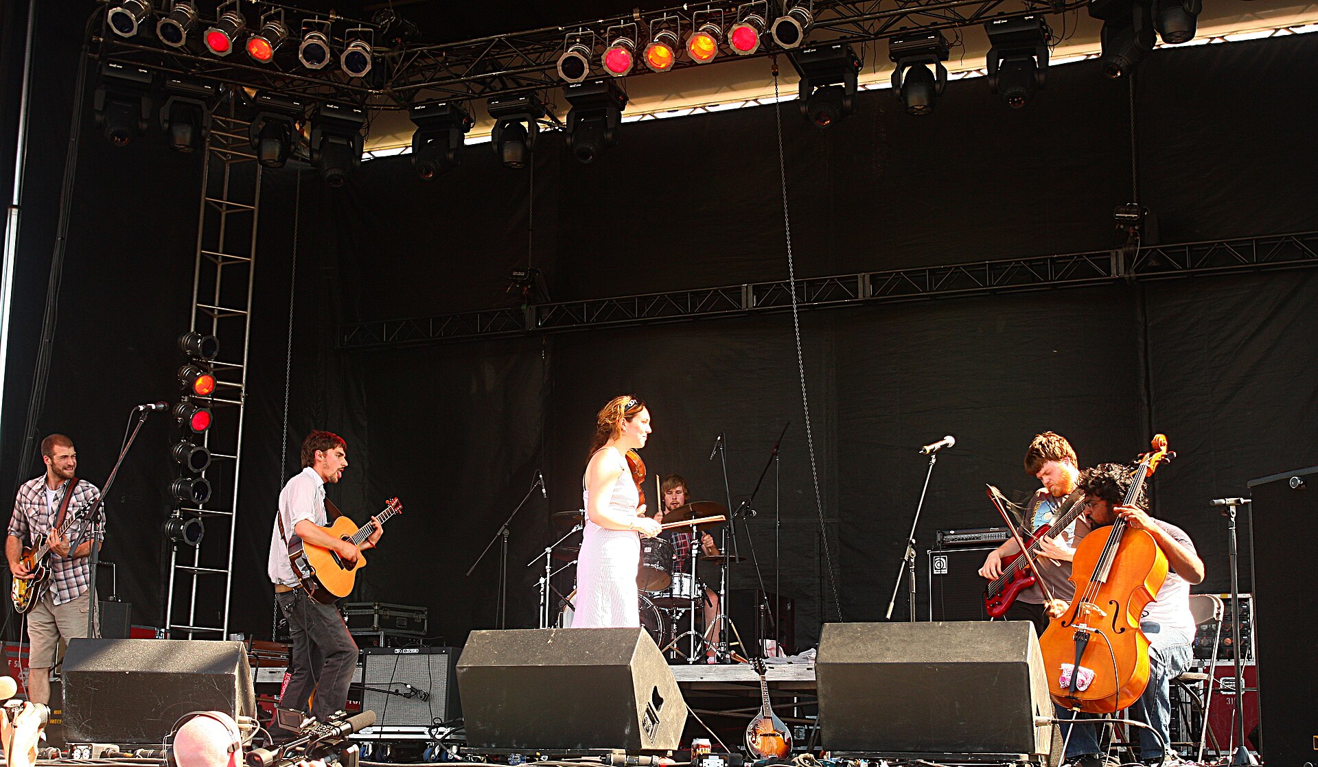 Hey Rosetta! spread across a daylit festival stage, with two guitarists to the left, a violinist in a white dress centre, a drummer behind and a cellist and bassist to the right.