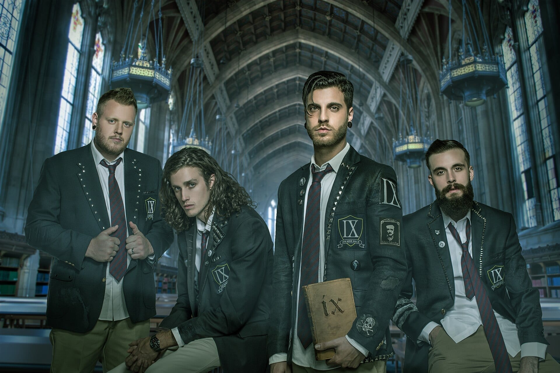 The four members of Ice Nine Kills pose in matching dark blazers with pinned buttons and patches in an ornate, cathedral-like hallway, one holding a weathered book marked with the Roman numeral IX.