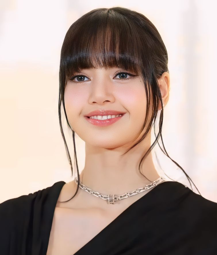 A close portrait of Lisa smiling, dark hair with a blunt fringe and loose strands framing her face, wearing a black top and a silver chain necklace.