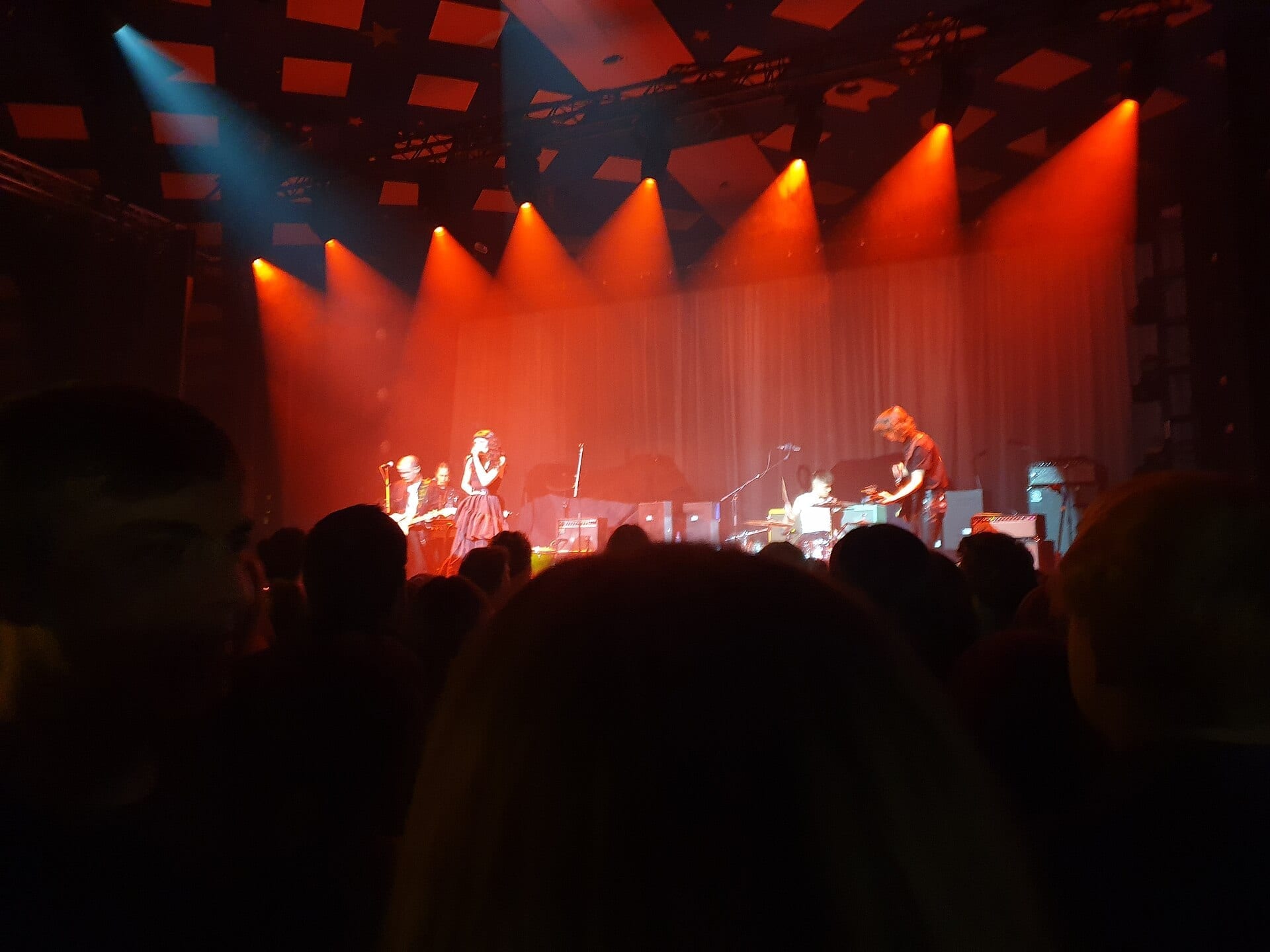 Lucia and the Best Boys perform on the Barrowland Ballroom stage, bathed in red light, seen from the crowd.