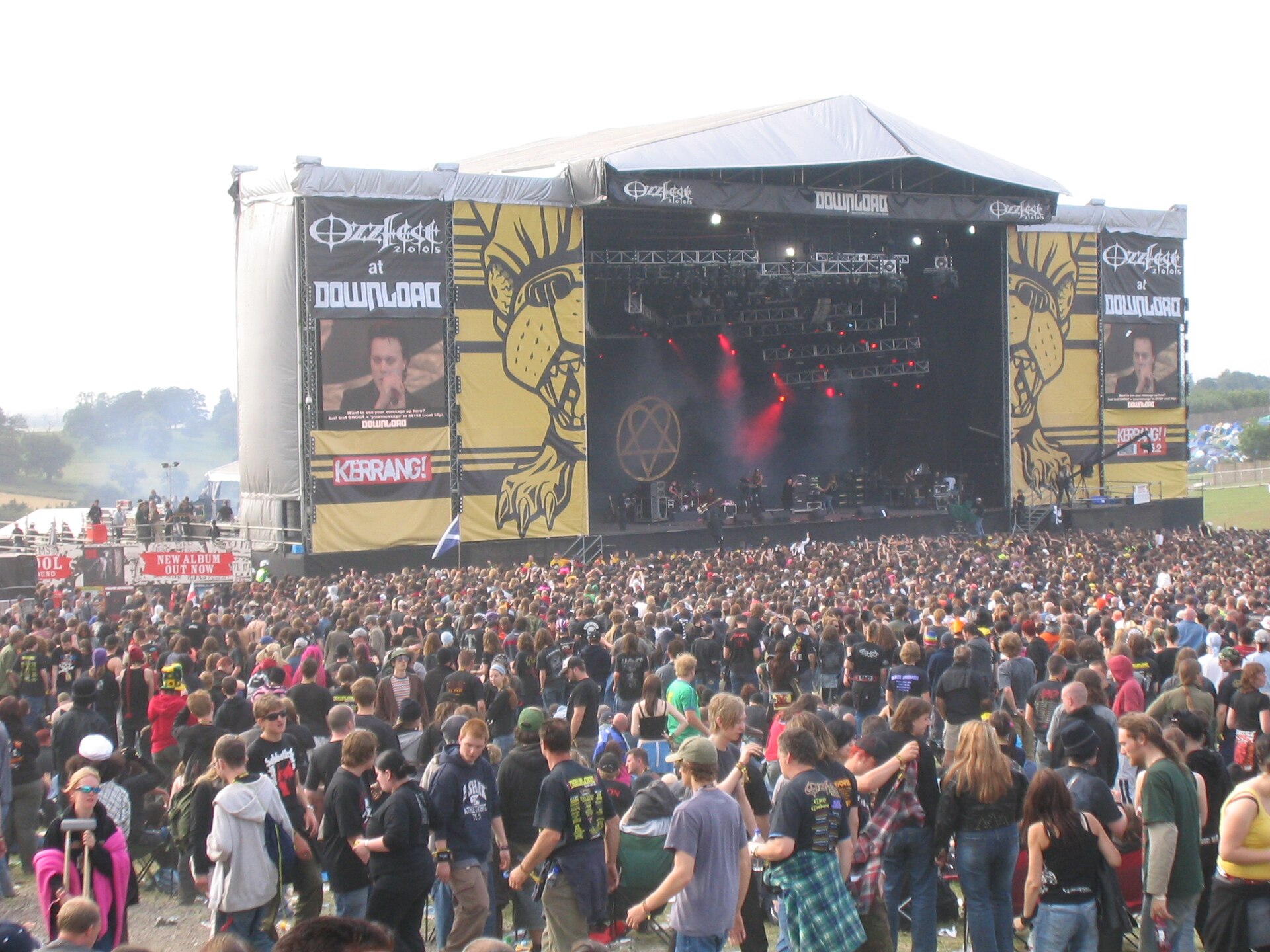 A large festival crowd in front of an outdoor main stage hung with banners reading Ozzfest 2005 at Download