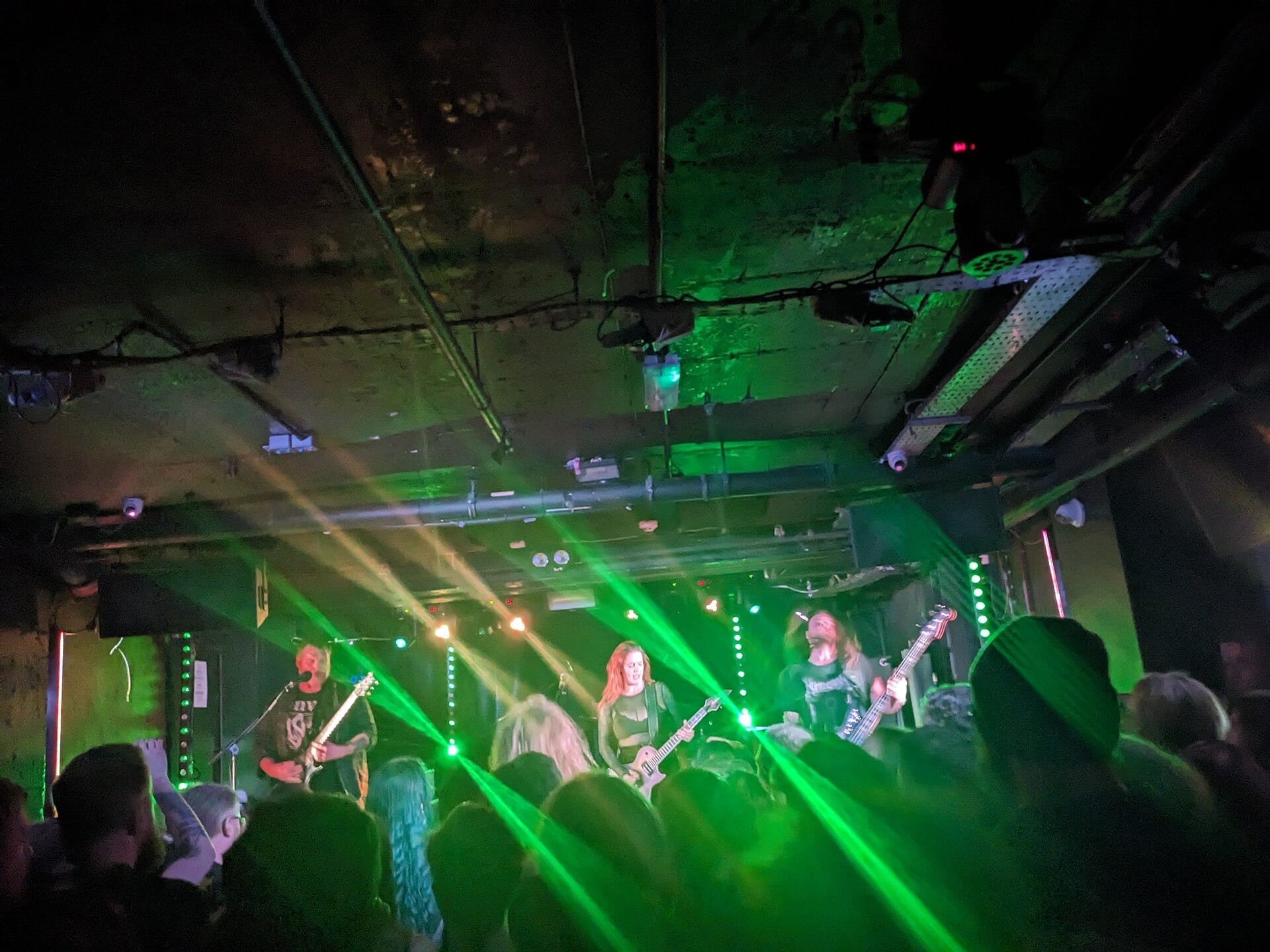 Svalbard performs on a small club stage lit by green laser beams, with Serena Cherry playing guitar at center.