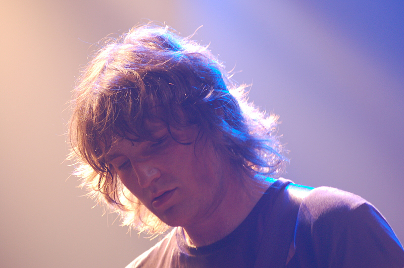 James Walsh of Starsailor sings with his eyes shut, long hair falling across his face under warm stage light.
