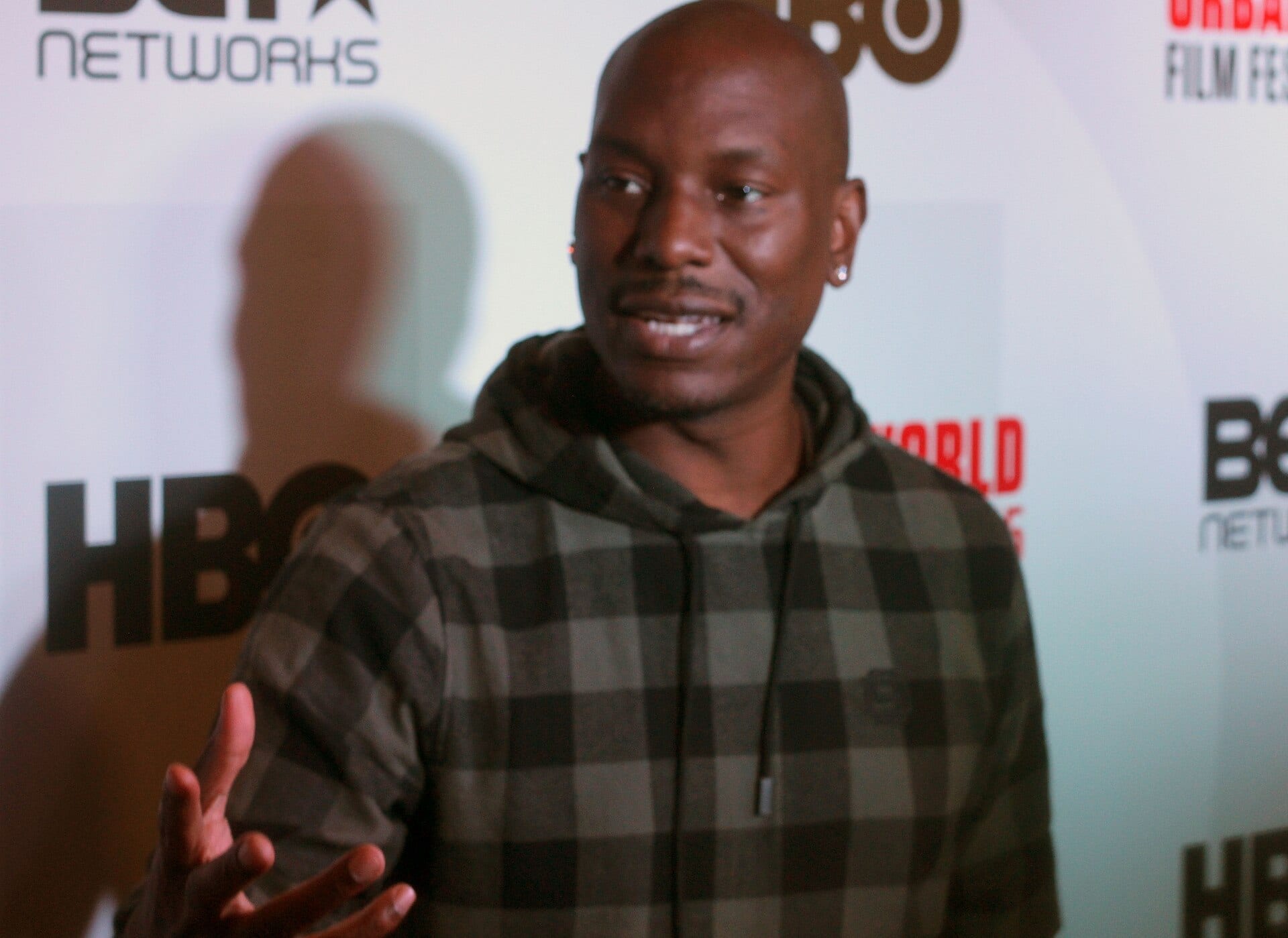 Tyrese Gibson smiles and gestures while speaking in front of an HBO and BET Networks step-and-repeat backdrop.